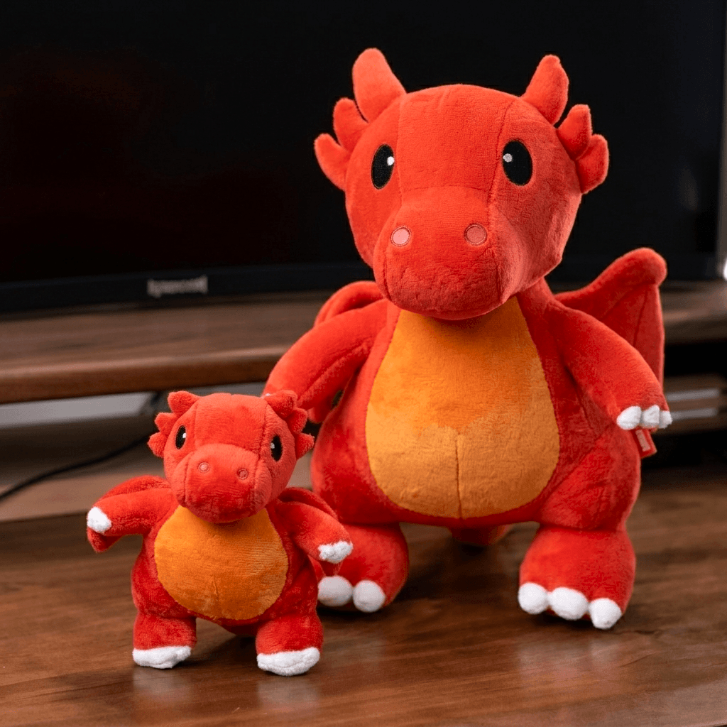 Two red plush dragons on a wooden surface with a blurred background