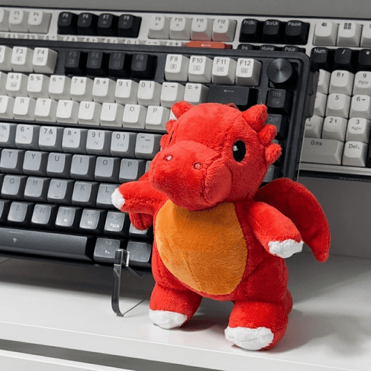 Red plush dragon toy on a desk with a keyboard in the background
