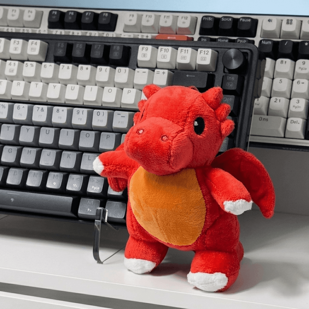 Red plush dragon toy on a desk with a keyboard in the background