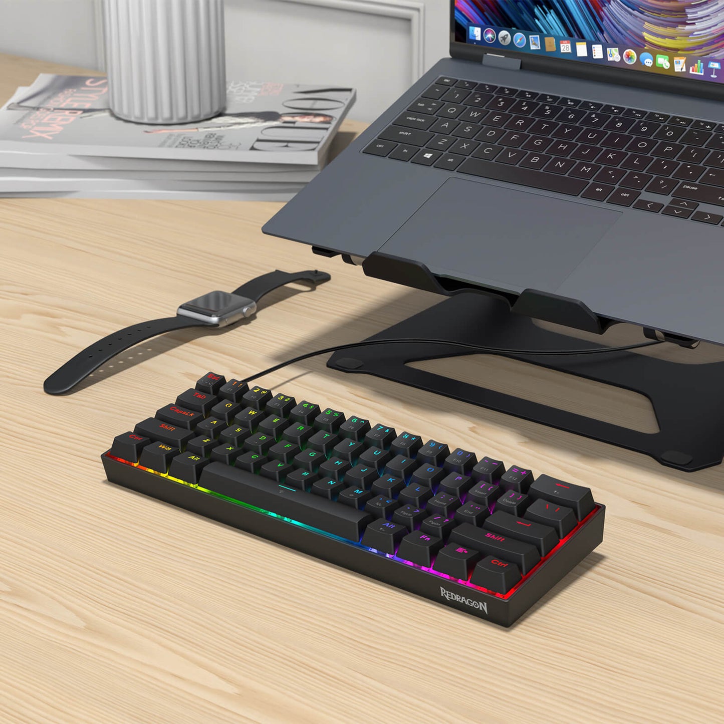 Keyboard with RGB lighting on a desk next to a laptop and smartwatch