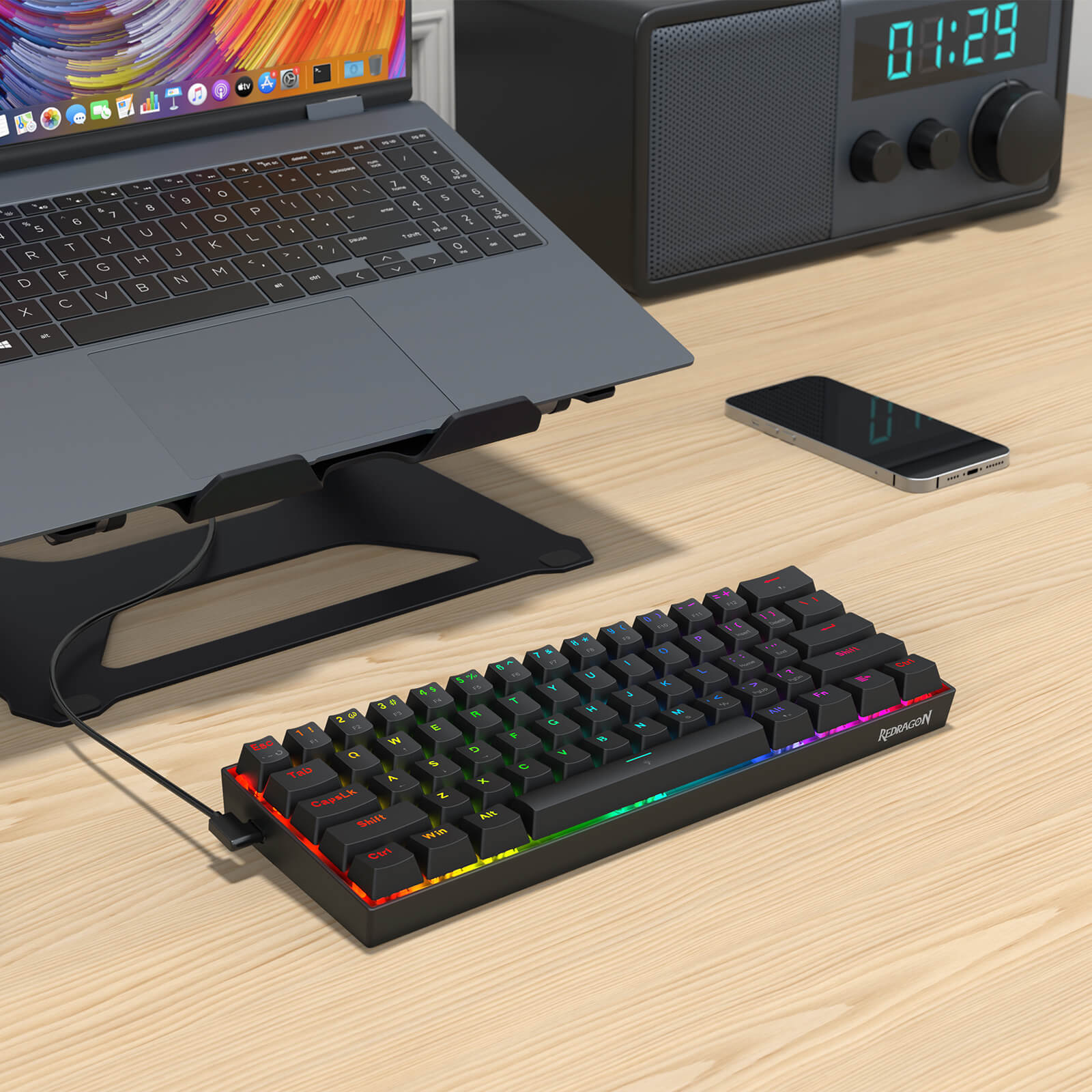 Laptop on a stand with a keyboard and smartphone on a wooden surface