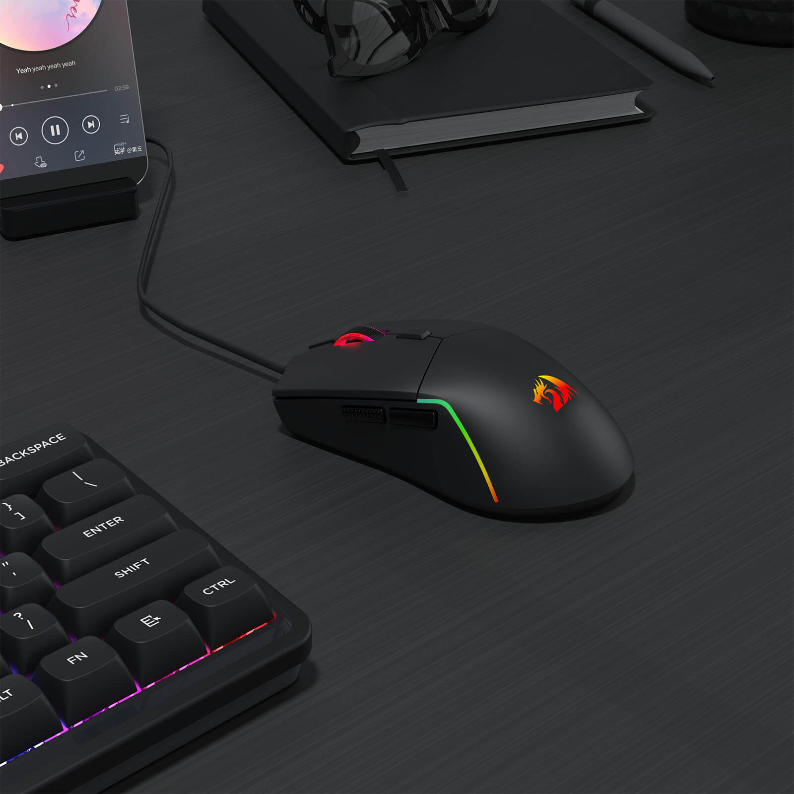 Redragon M730 Gaming mouse and keyboard on a dark surface with smartphone and notebook in the background