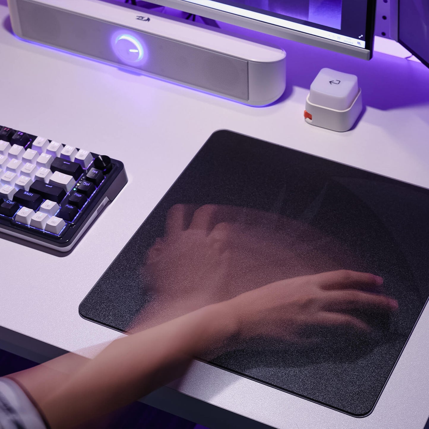 Person using a computer mouse on a desk with a keyboard and monitor in the background.