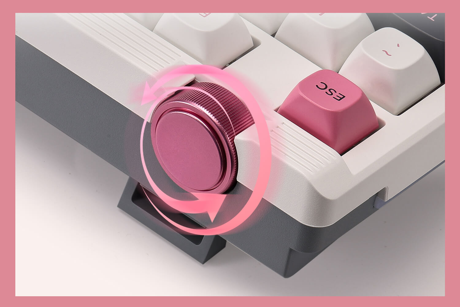 Close-up of a mechanical keyboard with a pink key and pink ring, on a light gray background.